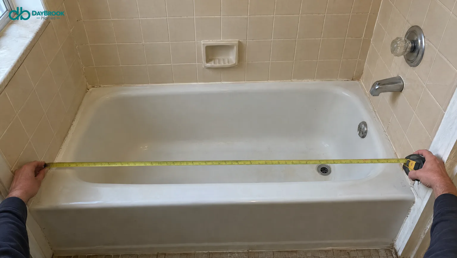Blog 20 Hands measuring an old bathtub alcove with a tape measure before a remodel