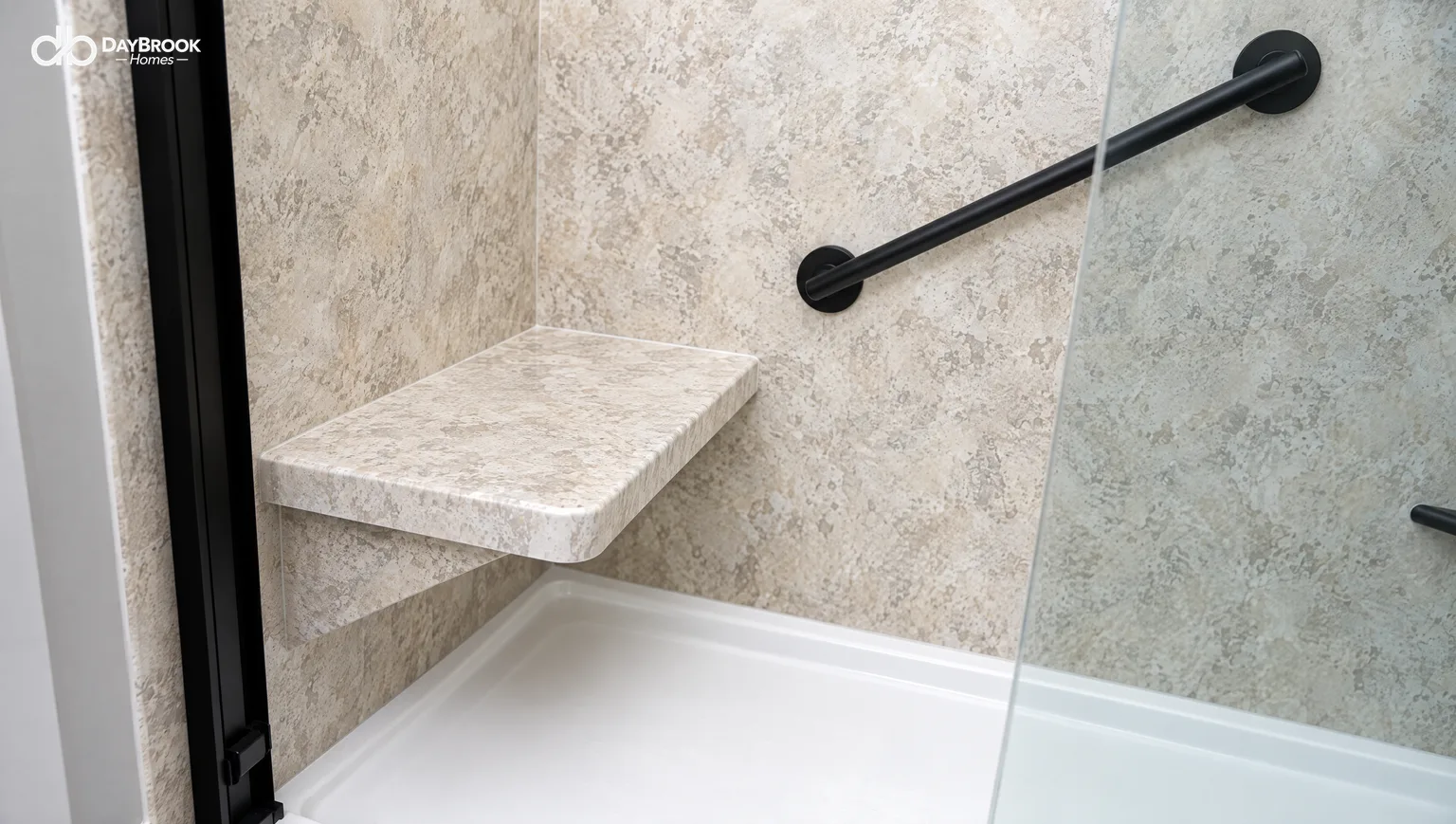 Solid wall-mounted shower seat in travertine-look panel material with a matte black grab bar above it